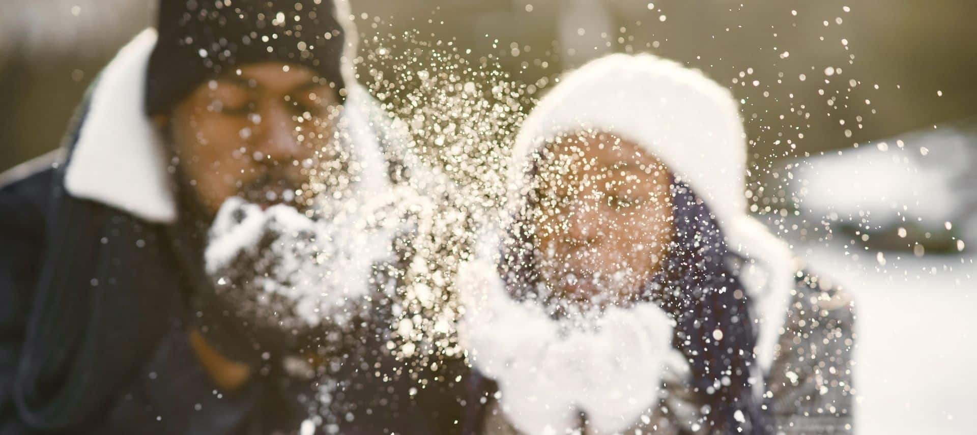 african-american couple blurred in background blowing snowflakes