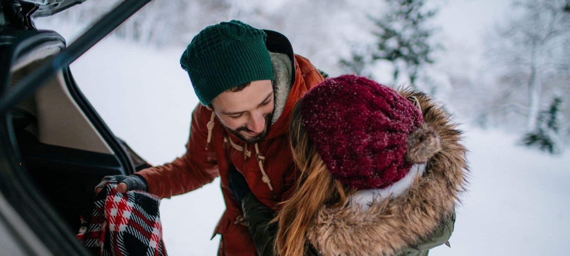 couple cuddling while packing car for winter getaway